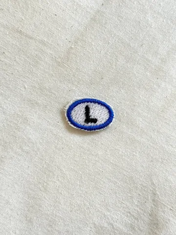 Ⓛ — embroidered artist emblem