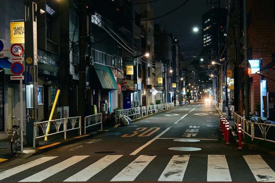 A street in Jingumae 2-chome at night, the yellow Jinny flags on the lit streetlamps